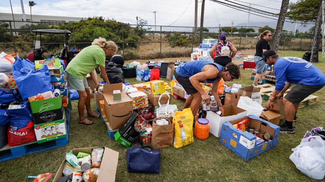 Volunteers stack canned goods at the War Memorial Stadium in Kahului.