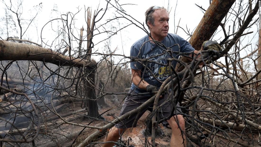 Zoltan Balogh clears away trees that were burned by the wildfire in Kula.