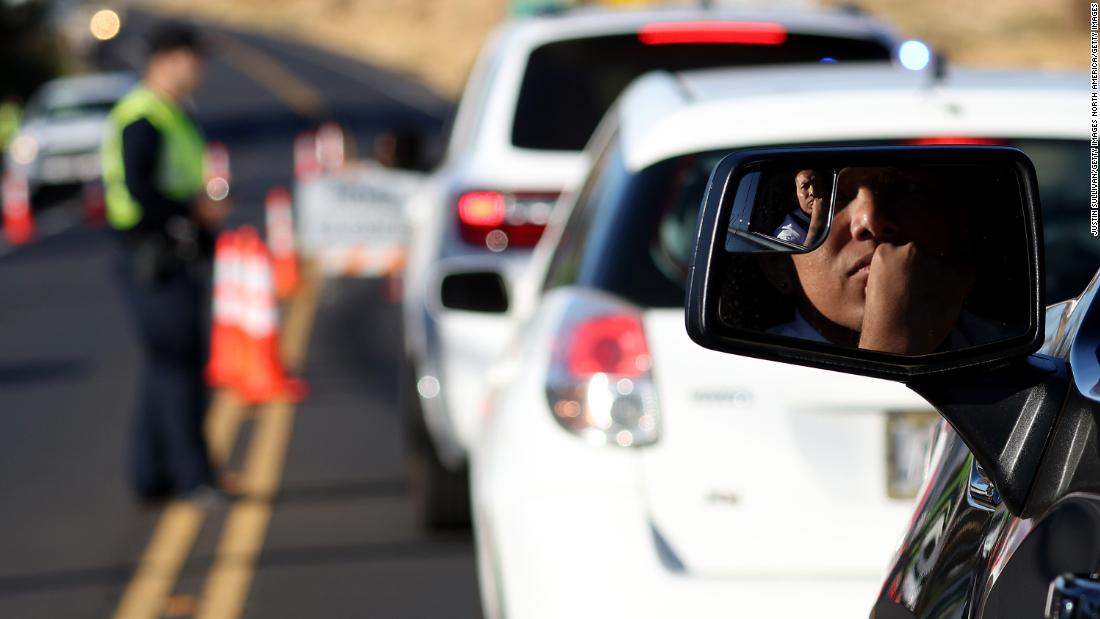People wait in line at a checkpoint to gain access to Lahaina on Saturday, August 12.