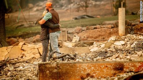 Victims of the Camp Fire embrace while searching through the remains of their Paradise, California, home on November 12, 2018. 