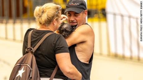 Two people evacuated by the fire hug their dog on Saturday in La Orotava.