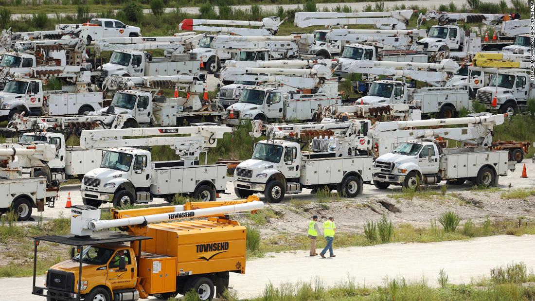 Electrical line technicians walk among hundreds of trucks at Duke Energy&#39;s staging location in Sumterville, Florida, on August 29.