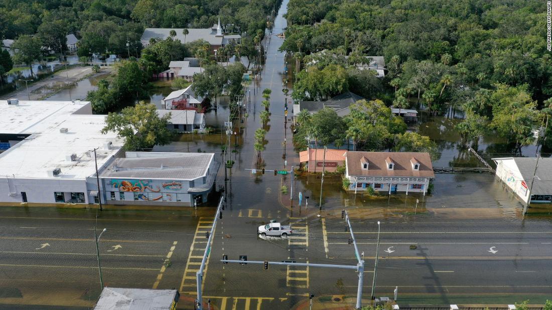 In an aerial view, a vehicle drives through a flooded street in downtown Crystal River on August 30.
