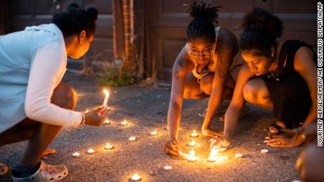 Sandriana McBroom, right, and Makhiya Mcbroom, center, light candles that spell out &quot;RIP Kiya&quot; at an August 25 vigil in Columbus, Ohio.