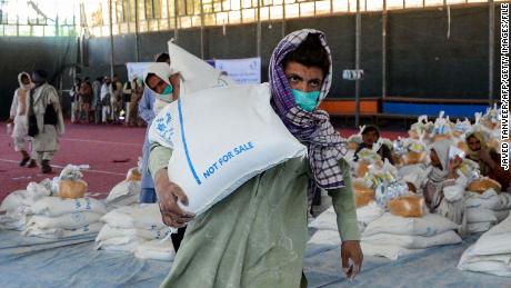 An Afghan man carries sacks of grains he received at a World Food Programme (WFP) facility in Kandahar on April 21, 2022.