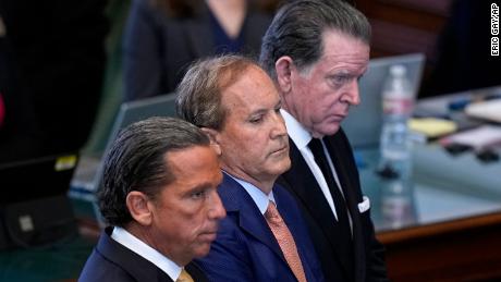 Texas state Attorney General Ken Paxton, center, stands between his attorneys Tony Buzbee, front, and Dan Cogdell, rear, as the articles of his impeachment are read during the his impeachment trial in the Senate Chamber at the Texas Capitol, Tuesday, Sept. 5, 2023, in Austin, Texas.