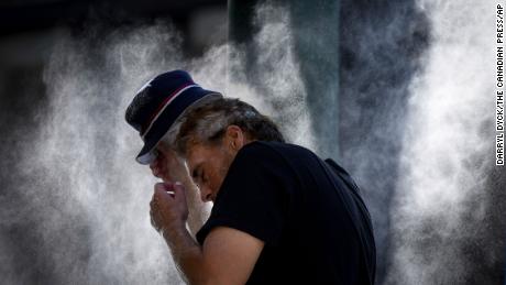A man cools off at a temporary misting station deployed by the city in the Downtown Eastside due to a heat wave, in Vancouver, British Columbia, Aug. 16, 2023. 