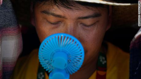 A volunteer uses a small fan to cool off from the intense heat, as he waits ahead of the Pope Francis arrival at Passeio Marítimo in Algés, just outside Lisbon on August 6, 2023.
