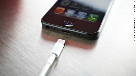 A newly released Apple iPhone 5 sits on a coffee shop countertop next to Apple&#39;s lightning connection cable in September 2012.
