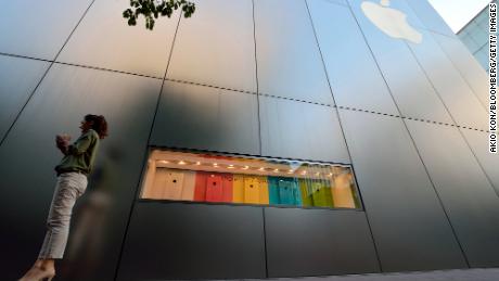 A woman uses her smartphone in front of a display for the Apple iPhone 5C outside the company&#39;s store in the Ginza district of Tokyo, Japan, on September 20, 2013.
