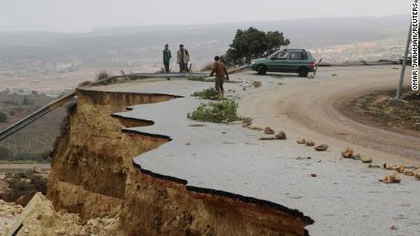People stand in a damaged road as a powerful storm and heavy rainfall flooded hit Shahhat city, Libya, September 11, 2023. 