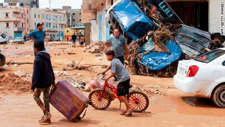 A boy pulls a suitcase past debris in a flash-flood damaged area in Derna, eastern Libya, on September 11, 2023. 