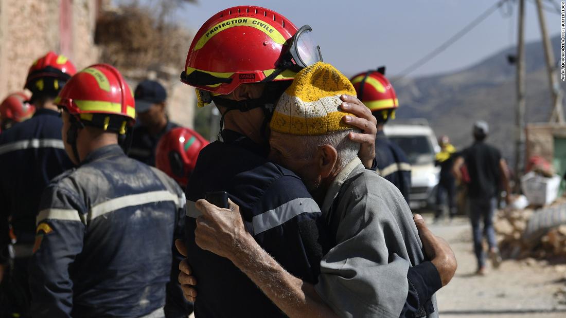 A man hugs a member of a civil protection team as it prepares to recover bodies in Imi N&#39;Tala on September 13.