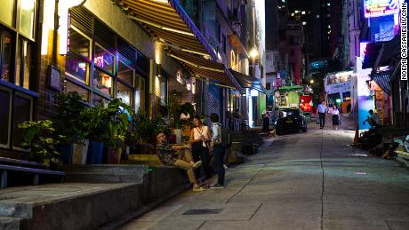 People gather outside a restaurant on a near-empty street in the Soho area of Hong Kong.