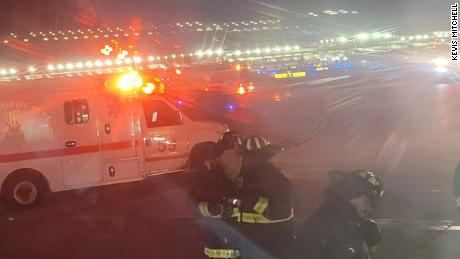 Looking out a window from his seat on the plane, passenger Kevis Mitchell took his photo of emergency responders arriving after the collision. 