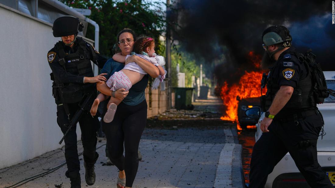 Police officers evacuate a woman and a child from a site hit by a rocket in Ashkelon on October 7.