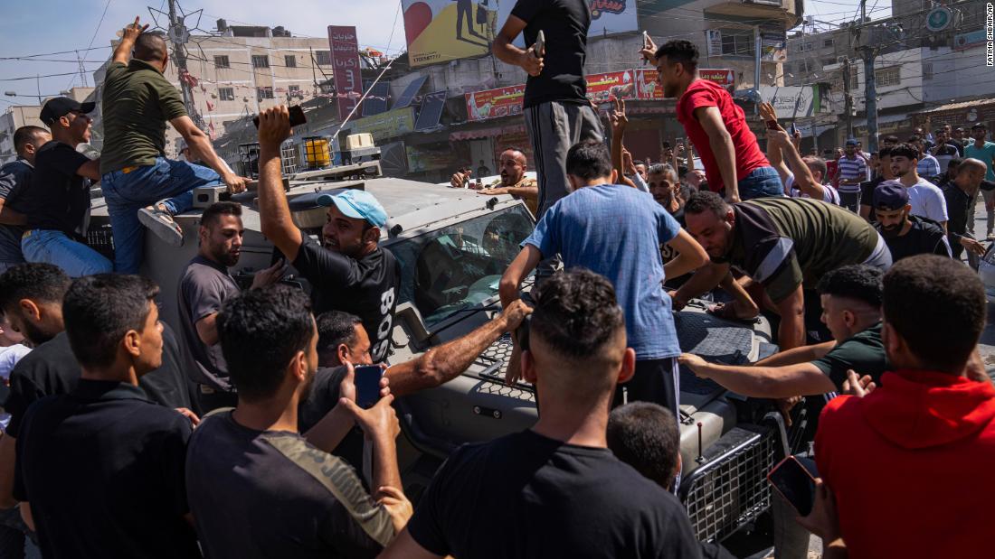 Palestinians gather around an Israeli army vehicle that Palestinian militants drove from Israel into Gaza on October 7.