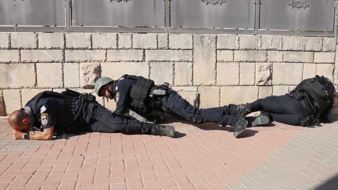 Israeli police take cover in Ashkelon as sirens wail while rockets are fired from Gaza into Israel on October 7.