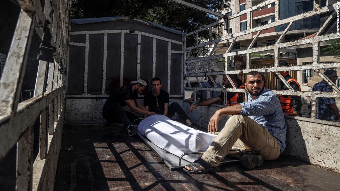 Outside of a hospital in Gaza, men sit next to the covered body of a Palestinian militant killed during Saturday&#39;s clashes.