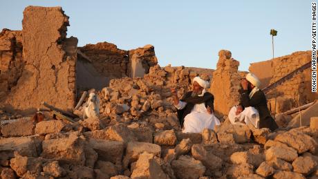 Residents sit at a damaged house after an earthquake in Sarbuland village of Zendeh Jan, district of Herat province, on October 7, 2023.