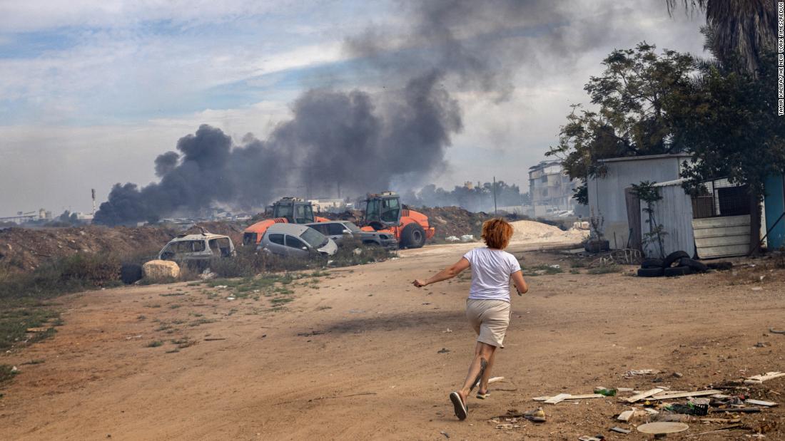 A woman runs to her family&#39;s reinforced concrete shelter moments after rocket sirens sounded in Ashkelon on October 7.