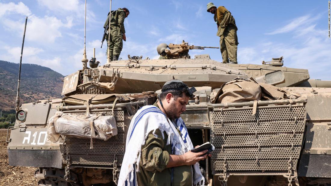 An Israeli soldier prays standing in front of a tank on the outskirts of the northern town of Kiryat Shmona on October 8.