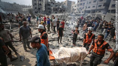 Palestinians carry a dead body after Israeli airstrikes hit al-Susi Mosque in Gaza on Monday.