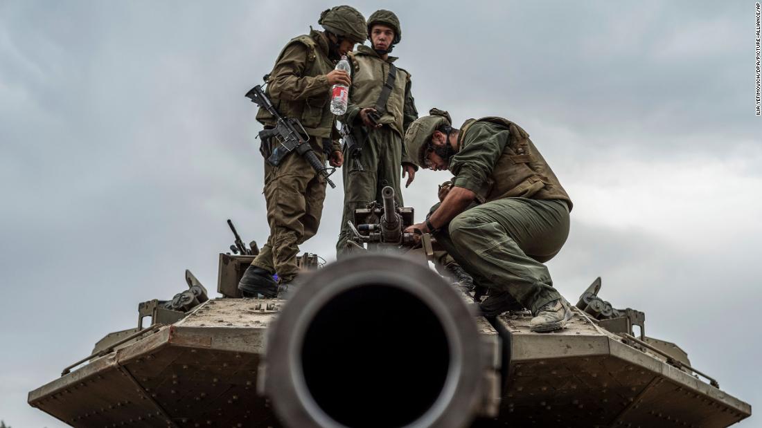 Israeli soldiers work on a tank at the border between Israel and Gaza on October 9.