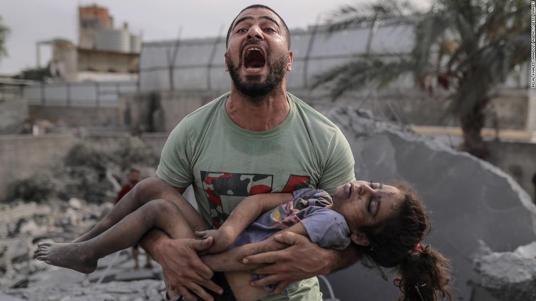 A Palestinian man reacts as he carries the body of his cousin who was pulled from the rubble after Israeli airstrikes in Gaza City on Monday, October 9.