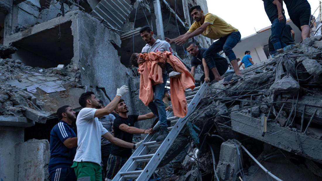 Palestinians rescue a young girl from the rubble of a destroyed residential building following an Israeli airstrike on October 10.