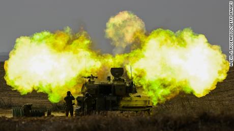 An IDF Artillery solider covers his ears as a shell is fired toward Gaza on October 11, near Netivot, Israel. 
