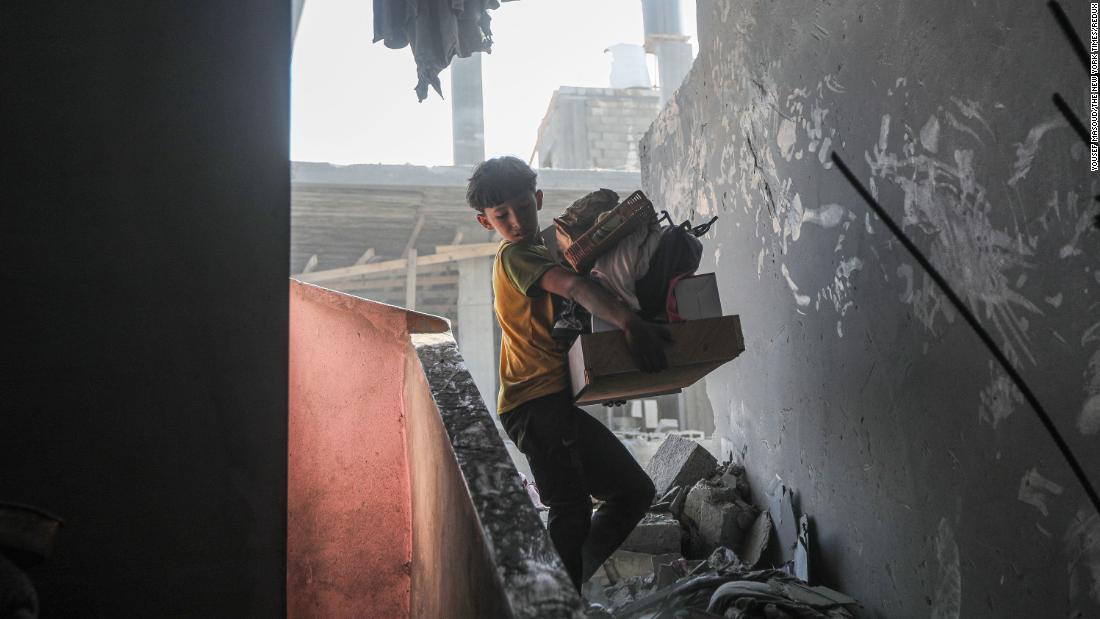 A boy carries salvaged belongings from the wreckage of his family&#39;s home in Khan Younis, Gaza, on October 11.
