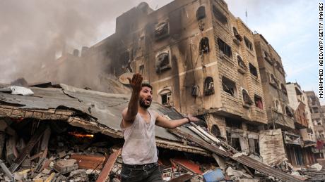 A man reacts outside a burning collapsed building following Israeli bombardment in Gaza City on October 11.