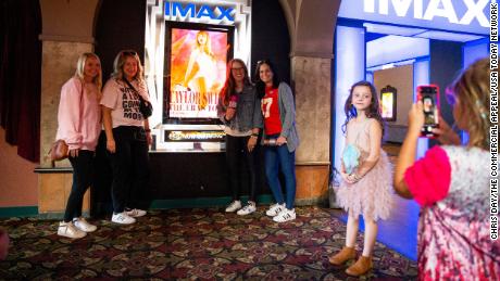 A young Taylor Swift fan takes a photo of the moms of their group next to the &quot;Taylor Swift: The Eras Tour&quot; poster before they go in to see the movie at Malco Paradiso Cinema Grill and IMAX in Memphis, Tenn., on Saturday, October 14, 2023.