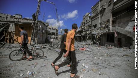 People walk amid the destruction of houses and streets in Khan Younis, located in the southern Gaza Strip.