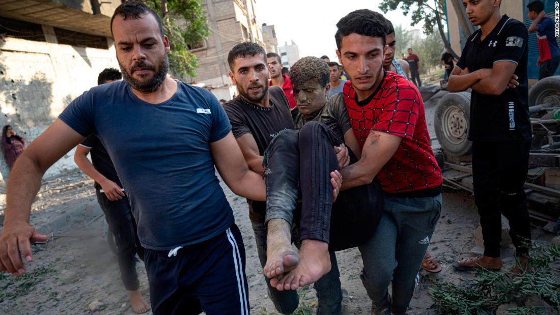 Palestinians carry a person wounded in Israeli airstrikes in Khan Younis, Gaza, on Monday, October 16.