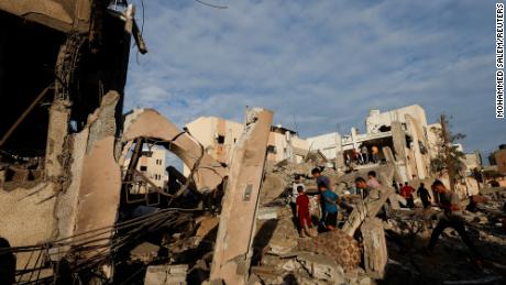 Palestinians search under the rubble of a building destroyed by Israeli strikes in Khan Younis in the southern Gaza Strip, October 17, 2023. 