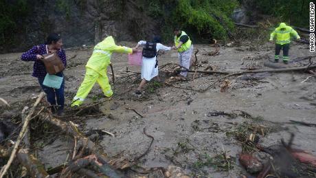 People get help crossing a highway blocked by a landslide triggered by Hurricane Otis near Acapulco on Wednesday.