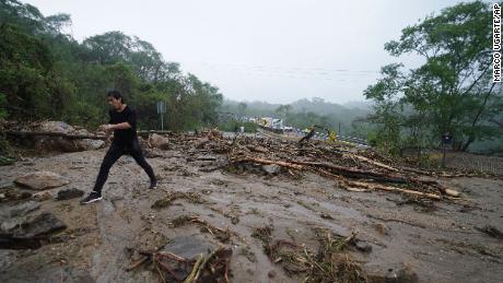 A man on Wednesday crosses a highway blocked by a landslide triggered by Hurricane Otis near Acapulco.