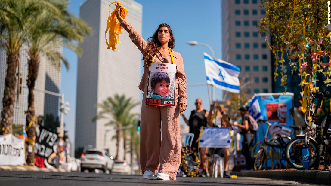 A woman with a photograph of a child who was abducted during the Hamas attack on Israel hands out yellow ribbons to passing drivers in central Tel Aviv, Israel, on October 25.&lt;br /&gt; 