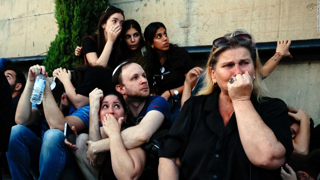People take cover as rocket sirens sound during the funeral of Sagiv Ben Zvi in Holon, Israel, on Thursday, October 26.
