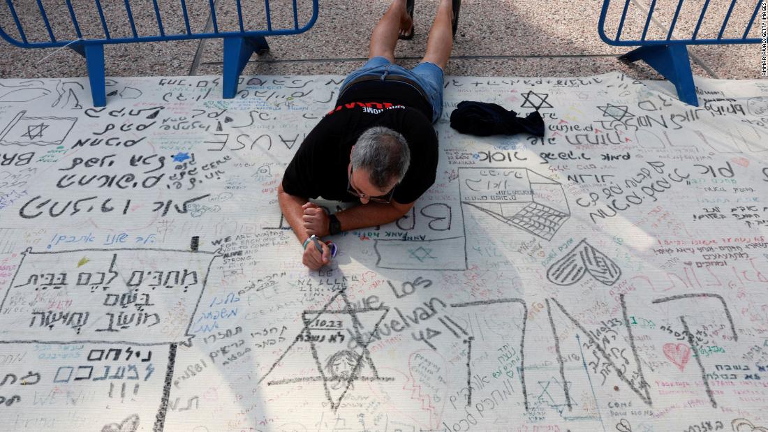 A man writes a message during a demonstration by family members and supporters of hostages who are being held in Gaza after they were kidnapped from Israel by Hamas gunmen, as they call for a dialogue with Israeli Prime Minister Benjamin Netanyahu and Defense Minister Yoav Gallant, in Tel Aviv, Israel on October 28.