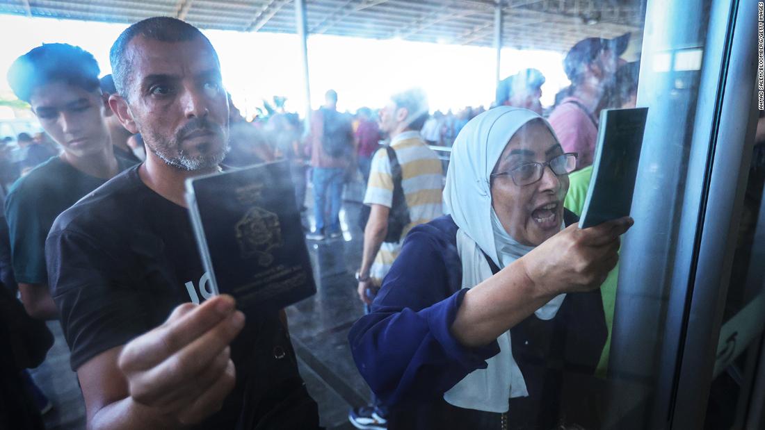Palestinians with dual citizenship show their passports while seeking permission to leave Gaza at the Rafah border crossing into Egypt, on November 1.