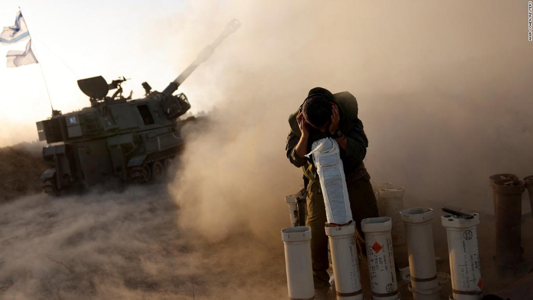 A soldier takes cover as an artillery unit fires from an undisclosed location near the Israel-Gaza border on November 6.