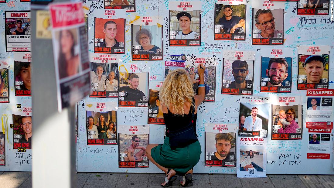 A woman in Tel Aviv writes on a photo of people kidnapped during the October 7 Hamas attack in Israel.