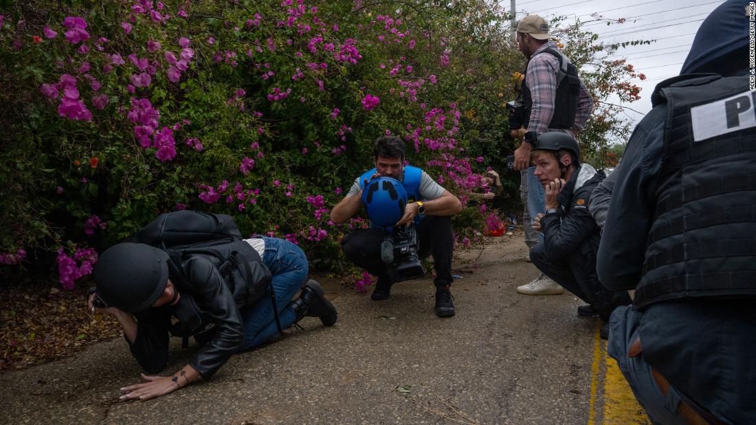 Foreign journalists get off a bus and take cover on the side of a road in Mavki&#39;im, Israel, after a siren warns of a rocket fired from Gaza on November 19.