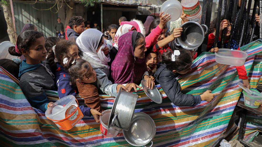 Palestinians clutching empty containers wait for food relief in Rafah, Gaza, on Sunday, November 19.