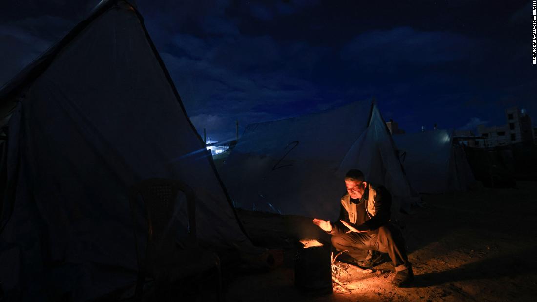 A displaced Palestinian man sits by tents sheltering people near the border between Israel and southern Gaza, in Khan Younis on November 27.