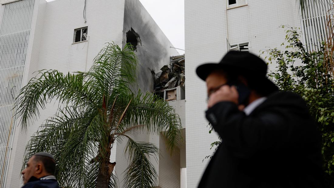 People walk past a building damaged in a rocket attack in Ashkelon, Israel, on December 5.