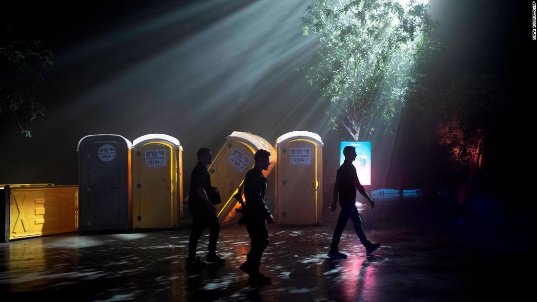 Security guards and a member of Israeli security forces pass a display of toppled toilets during a press tour of the 06:29 memorial recreating the site of the Nova music festival massacre in Tel Aviv, Israel, on December 6.